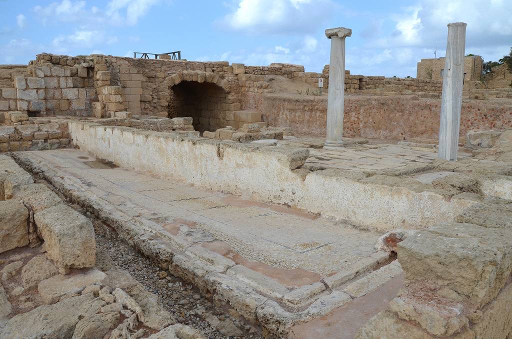 The public latrine used during the Roman and Byzantine periods. Marble benches were set along the southern and western walls of the latrine. Water flushed through its channels laid a the bottom of the walls and connecting with the main sewer beneath the decumanus street.