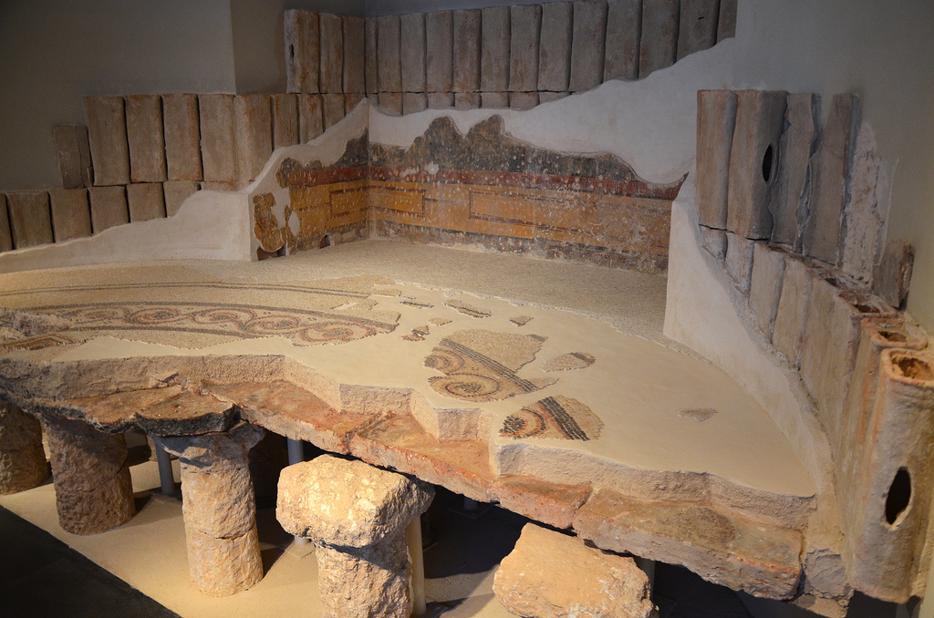 Reconstruction of a part of the round hot room (caldarium) from Herod's bathhouse at Herodium with remains of the frescoes and flues from the walls of the room and a mosaic floor decorated with scrolls, 1st century BC. Israel Museum, Jerusalem.