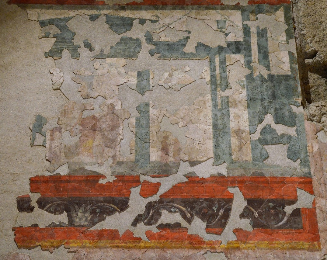 South wall of the “Large oecus” depicting a stage-like structure with human figures standing inside the central recess. One of the female figure wears a clock as well as a rich diadem and necklace while others are carrying votive offerings.