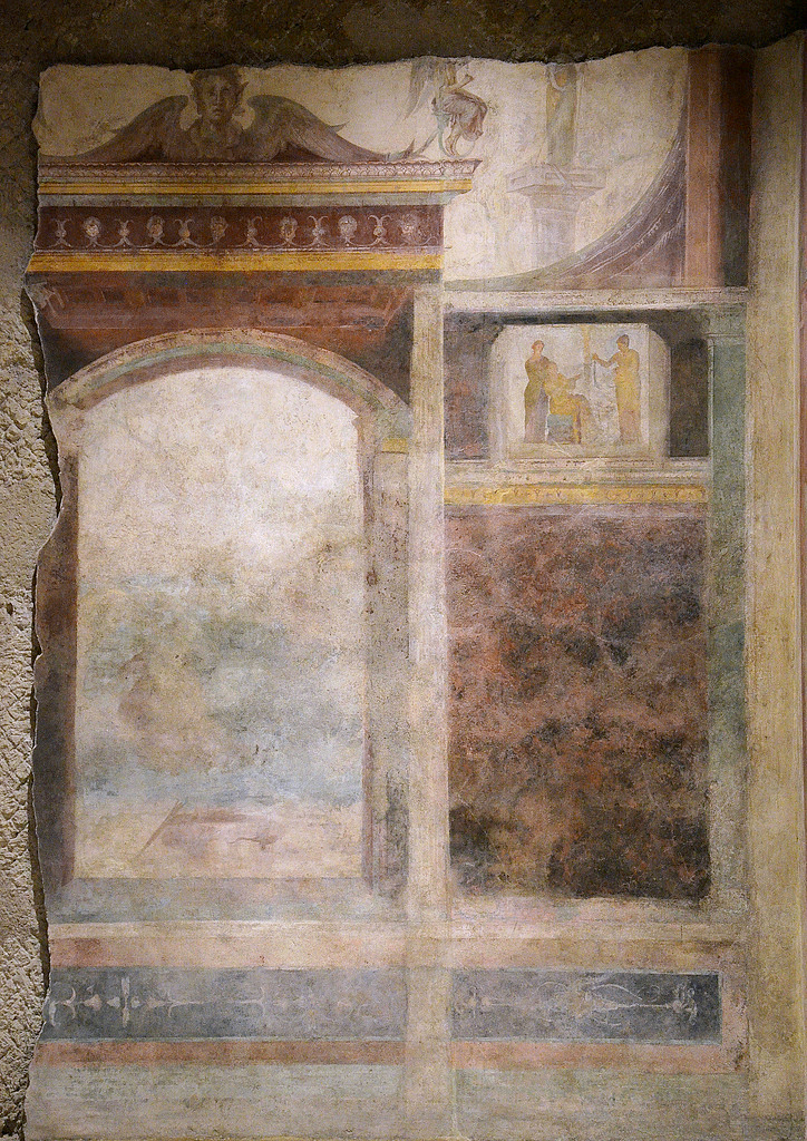 Detail of wall painting on the back wall of the tablinum. Around the central panel (now totally illegible) are backdrops of illusionistic architecture and small panels with ritual scenes.
